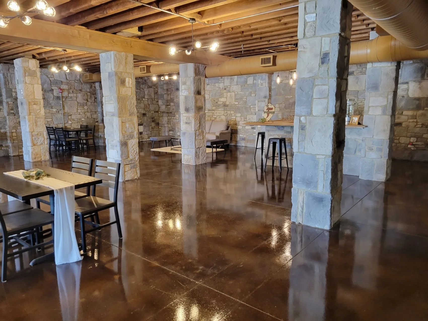 The Stone Room: a stone-pillared lower level with polished floors and intimate seating